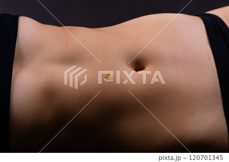 Beautiful seductive young female makes a honey on a black background. Drops of honey on her belly. 120701345