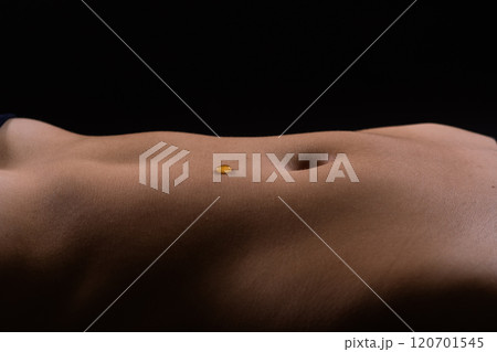 Beautiful seductive young female makes a honey on a black background. Drops of honey on her belly. 120701545