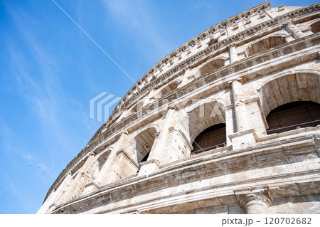 Visitors gazing up at the Colosseum's majestic structure, showcasing its iconic architecture against a bright blue sky. This ancient amphitheater stands as a testament to Rome's rich history. Visitors gazing up at the Colosseum's majestic structure, showcasing its iconic architecture against a bright blue sky. This ancient amphitheater stands as a testament to Rome's rich history. 120702682