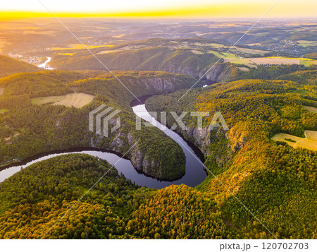 A breathtaking sunset bathes the Vltava River in golden hues, casting reflections on its winding path. Surrounded by lush hills and valleys, this serene moment captures the natural beauty of Czechia. A breathtaking sunset bathes the Vltava River in golden hues, casting reflections on its winding path. Surrounded by lush hills and valleys, this serene moment captures the natural beauty of Czechia. 120702703