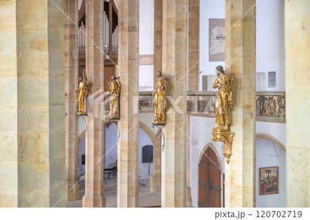 The late Gothic interior of the Church of the Assumption of the Virgin Mary in Most features tall columns and golden statues, highlighting its architectural beauty and historical significance. The late Gothic interior of the Church of the Assumption of the Virgin Mary in Most features tall columns and golden statues, highlighting its architectural beauty and historical significance. 120702719