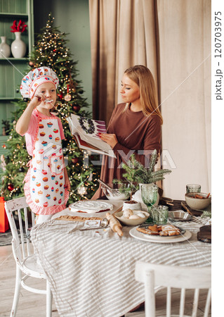 a girl child with mom in the kitchen with a 120703975