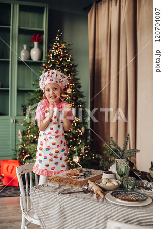 a girl child in the kitchen with a Christmas tree 120704007
