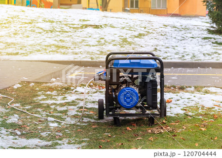 Portable gasoline or diesel generator to provide electricity in city. Problem with electricity. Winter. Sunny day. 120704444