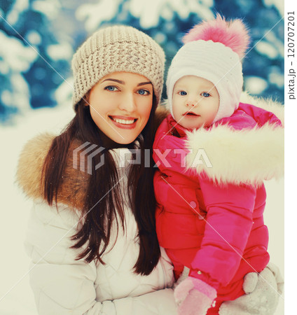 Winter portrait happy smiling mother and baby on hands over snowy christmas tree background 120707201