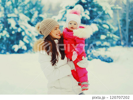 Winter portrait happy smiling mother with baby on her hands over snowy christmas tree background 120707202