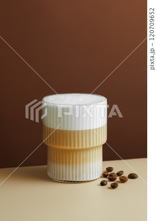glass of cappuccino and coffee beans near on table 120709652
