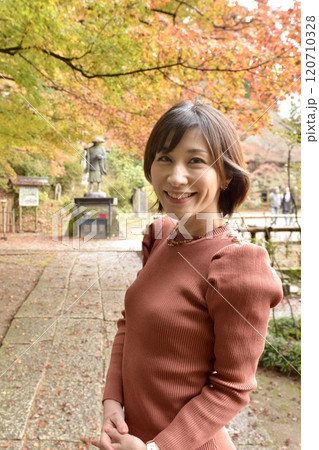 紅葉とタイトワンピースを着た若い女性 120710328