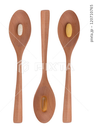 pills in wooden spoons isolated 120710765