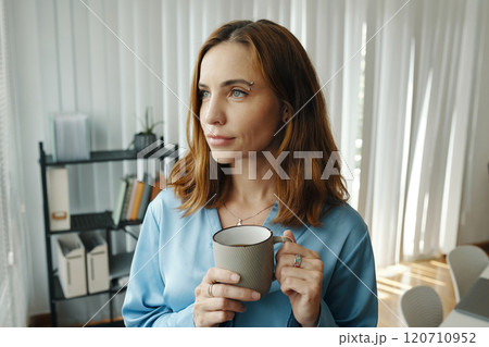 Woman Reflecting While Holding Coffee Mug in Modern Home Woman Reflecting While Holding Coffee Mug in Modern Home 120710952