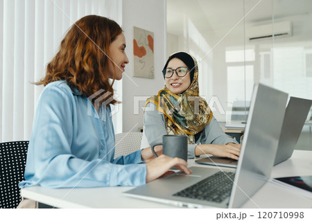 Two Women Discussing Work in Modern Office Setting Two Women Discussing Work in Modern Office Setting 120710998