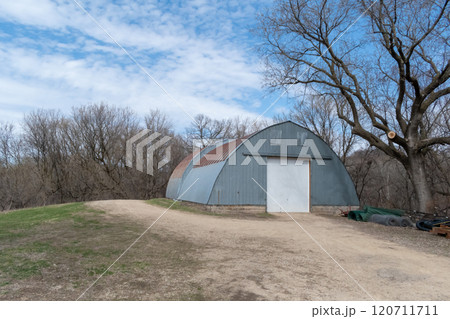 Rustic Quonset in Serene Countryside with Clear Blue Sky and Surrounding Trees. Rustic Quonset in Serene Countryside with Clear Blue Sky and Surrounding Trees. 120711711