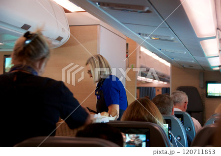 Above the Clouds, November 24, 2018: Inside an Airplane Economy Class Cabin with Flight Attendants Serving Passengers 120711853