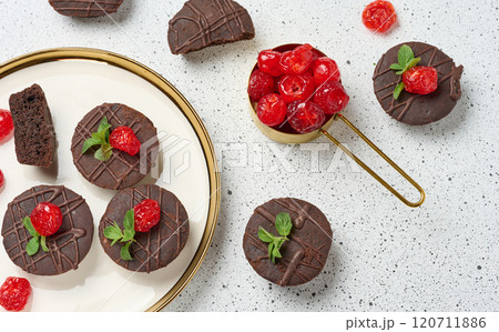 Chocolate brownies with the top adorned by a red juicy cherry and mint leaves, white background, top view 120711886