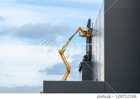 Two workers in hard hats mount elements of outdoor video advertising Two workers in hard hats mount elements of outdoor video advertising 120712166