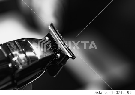 Close-up of a hair clipper preparing for a haircut in a barbershop setting Close-up of a hair clipper preparing for a haircut in a barbershop setting 120712199
