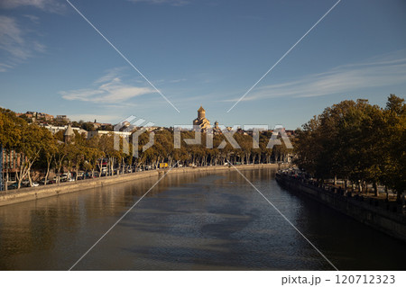 Golden autumn hues reflect in the tranquil waters of Tbilisi, showcasing the beauty of nature and architecture Golden autumn hues reflect in the tranquil waters of Tbilisi, showcasing the beauty of nature and architecture 120712323