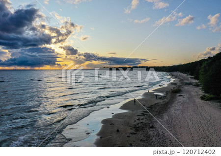 Serene sunset over tranquil lake with gentle waves and sandy beach inviting evening strolls 120712402