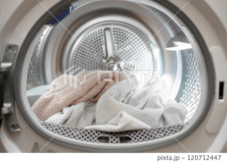 View of the tumble dryer or washing machine with the door open and a towel inside View of the tumble dryer or washing machine with the door open and a towel inside 120712447