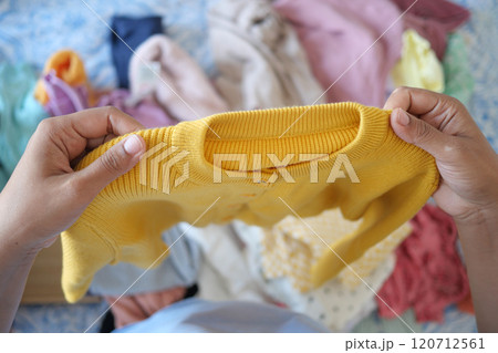 Organizing and Sorting Colorful Clothing A CloseUp Observational Look at a Yellow Sweater Organizing and Sorting Colorful Clothing A CloseUp Observational Look at a Yellow Sweater 120712561