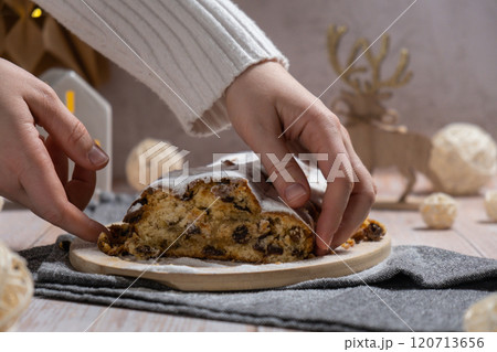 Female hand taking slice of Homemade Christmas traditional cake pie with marzipan nuts and dried fruits pastry dessert stollen. Winter holidays season atmosphere. Delicious tasty composition home 120713656
