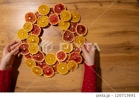 Handmade Christmas wreath from dried orange grapefruit slices. Festive holiday preparation craft master class of creative making decor. Hands-on activities sustainable responsible holiday gift Handmade Christmas wreath from dried orange grapefruit slices. Festive holiday preparation craft master class of creative making decor. Hands-on activities sustainable responsible holiday gift 120713691