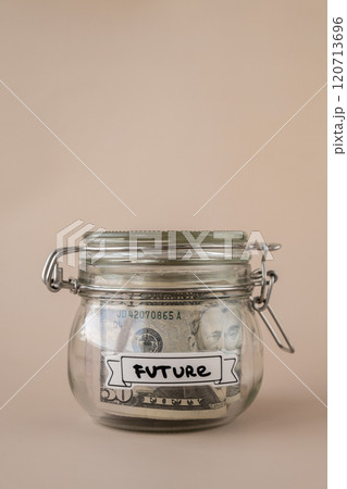 Glass jar full of American currency dollars cash banknote with text FUTURE. Preparation saving money. Moderate consumption and economy Glass jar full of American currency dollars cash banknote with text FUTURE. Preparation saving money. Moderate consumption and economy 120713696
