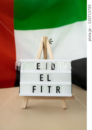 Message Lightbox EID EL FITR - Eid Mubarak - Happy Holidays text frame on United Arab Emirates waving flag made from silk material. Public holiday celebration background. The National Flag of UAE. 120713785