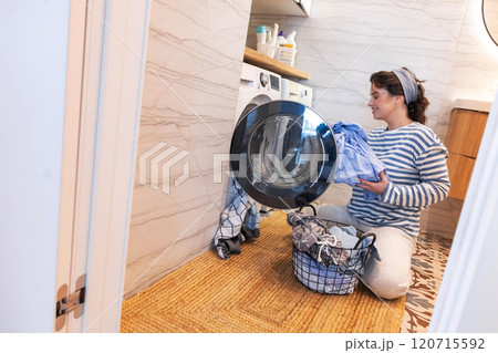Smiling woman housewife cleaning linen textile clothes putting washing machine and dryer at laundry Smiling woman housewife cleaning linen textile clothes putting washing machine and dryer at laundry 120715592