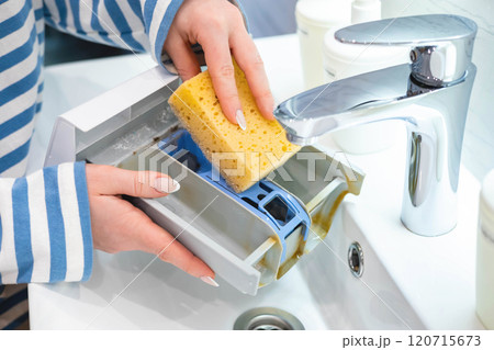 Housewife hands cleaning plastic container of washing machine use sponge and water at bathroom sink 120715673