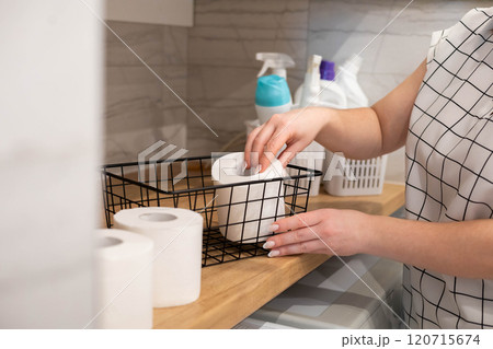 Female housewife hands arrangement toilet paper roll to metallic basket for comfortable storage 120715674