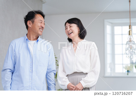 家のリビングで過ごす笑顔のミドル夫婦 家のリビングで過ごす笑顔のミドル夫婦 120716207