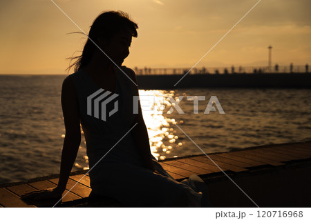 港で夕日を眺める女性 港で夕日を眺める女性 120716968