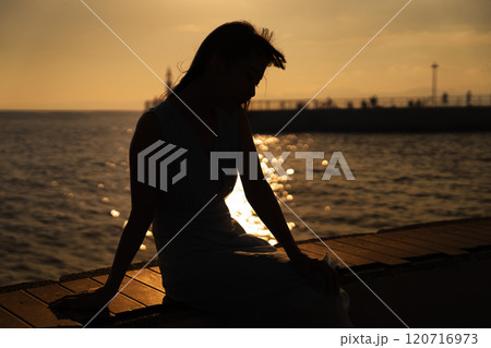港で夕日を眺める女性 港で夕日を眺める女性 120716973