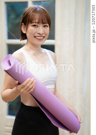 ヨガマットを持つ若い女性 120717305