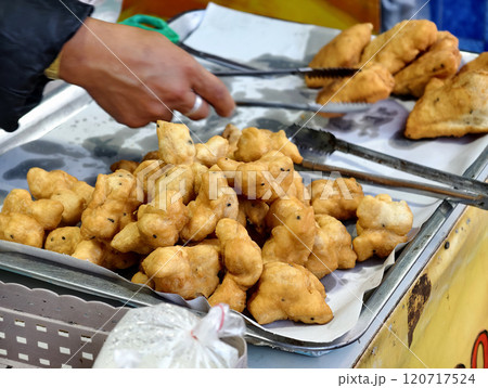 A vendor is placing freshly fried Chinese crullers into a bag to sell to a customer A vendor is placing freshly fried Chinese crullers into a bag to sell to a customer 120717524