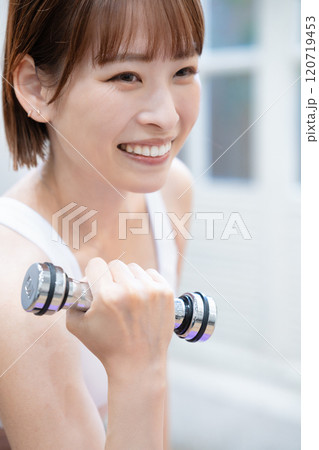 ダンベルでトレーニングする若い女性 120719453