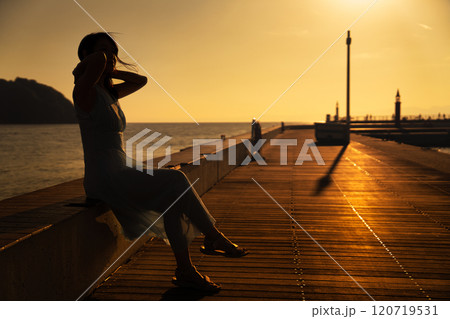 海のデッキで夕日を眺める女性 海のデッキで夕日を眺める女性 120719531