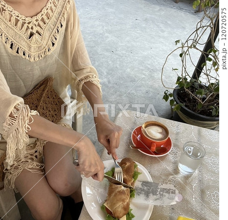 ビーチ沿いのカフェでモーニングしている女性 120720575