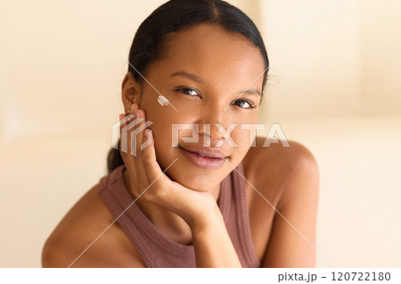 Young Woman Applying Face Cream With Serene Expression And Glowing Skin 120722180