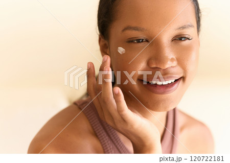 Smiling Woman Applying Face Cream for Glowing Skin and Self-Care 120722181