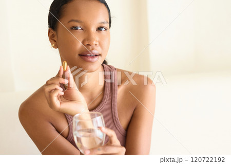Young Woman Holding Vitamin Supplement and Glass of Water Indoors 120722192