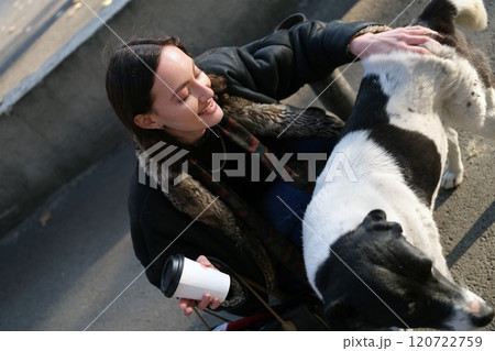 A Young Woman is Gently Petting a Cute Dog in a Lively Urban Setting Surrounded by Many People A Young Woman is Gently Petting a Cute Dog in a Lively Urban Setting Surrounded by Many People 120722759