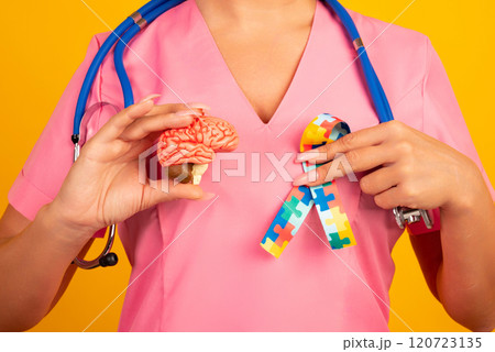 Female doctor is holding anatomical model human brain with Puzzle pattern ribbon . Help and care concept 120723135