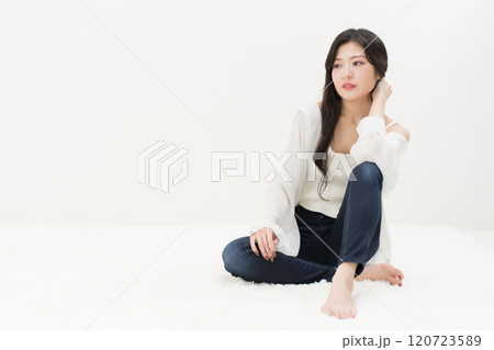 スキニージーンズ・ジーパン・デニムパンツをはいて胡座をかいて座る若い女性 スキニージーンズ・ジーパン・デニムパンツをはいて胡座をかいて座る若い女性 120723589