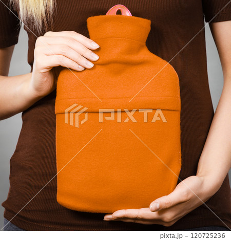 Woman holding warm orange hot water bottle Woman holding warm orange hot water bottle 120725236