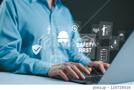 Safety First Concept. Work safety, Man typing on laptop with digital icons related to safety, protection, and regulations, including a hard hat, shield, and checklist, representing workplace safety. 120726016