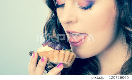 Cute girl holds fruit cake in hand on blue Cute girl holds fruit cake in hand on blue 120726060