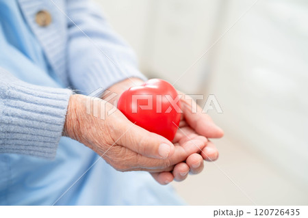 Asian elder senior woman patient holding red heart in hospital. Asian elder senior woman patient holding red heart in hospital. 120726435