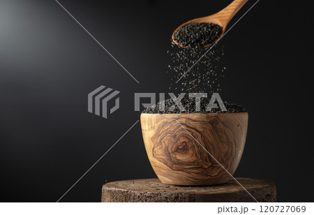 Black sesame is poured in wooden bowl. 120727069